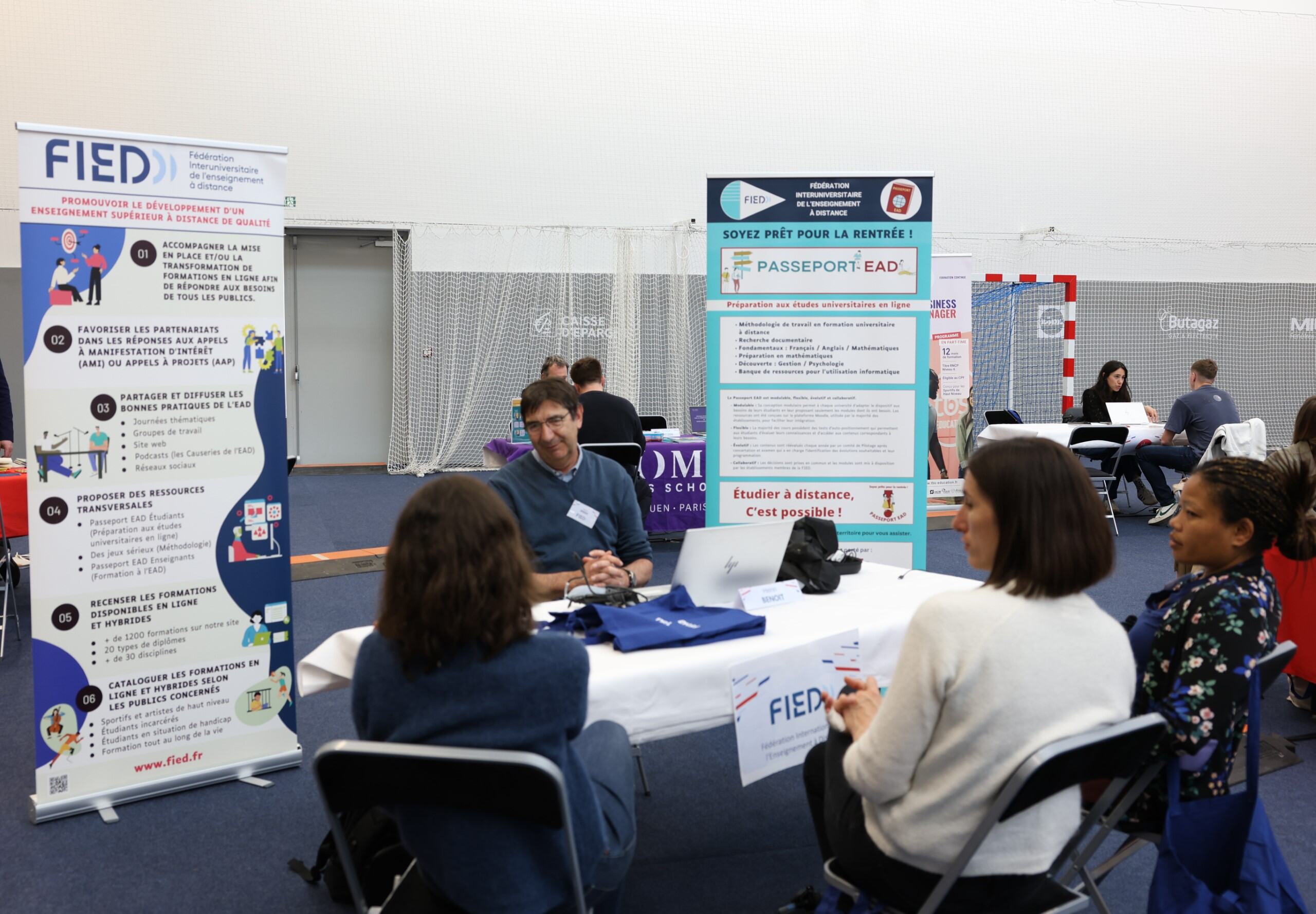 Stand FIED -Henri Benoit présente la FIED à des personnes au Forum Formation – Insertion – Reconversion